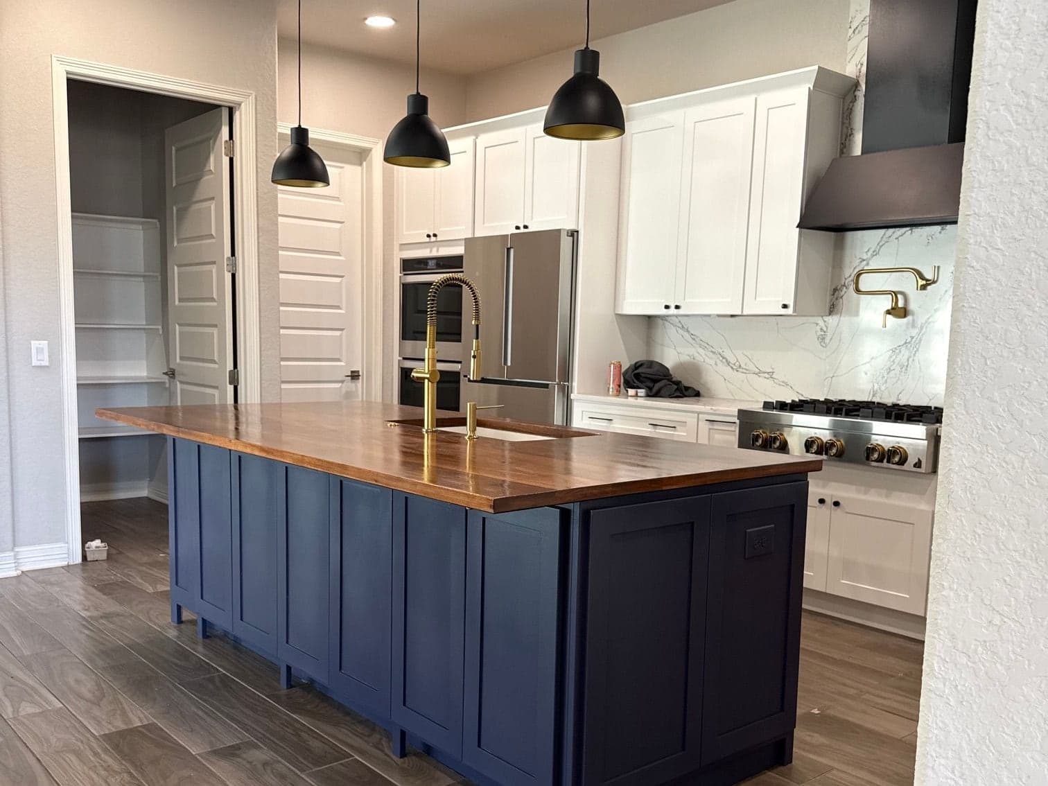 A kitchen remodel by Avanelle: a navy island, a wood top and brass fixtures